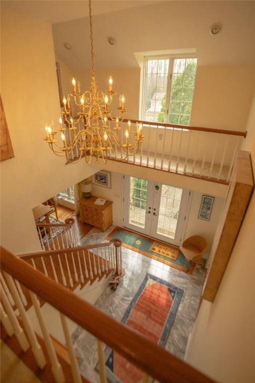 foyer entrance featuring french doors, a high ceiling, a chandelier, and stairs