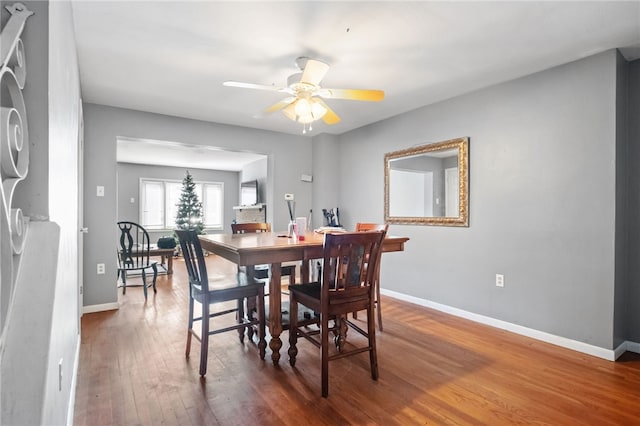 dining space featuring hardwood / wood-style floors, a ceiling fan, and baseboards