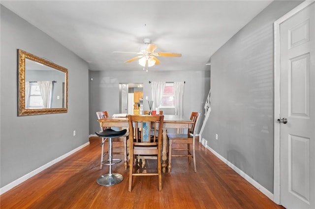 dining space with wood finished floors, a ceiling fan, baseboards, and a wealth of natural light