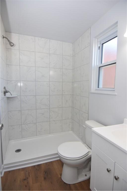 bathroom with vanity, toilet, wood finished floors, and a stall shower