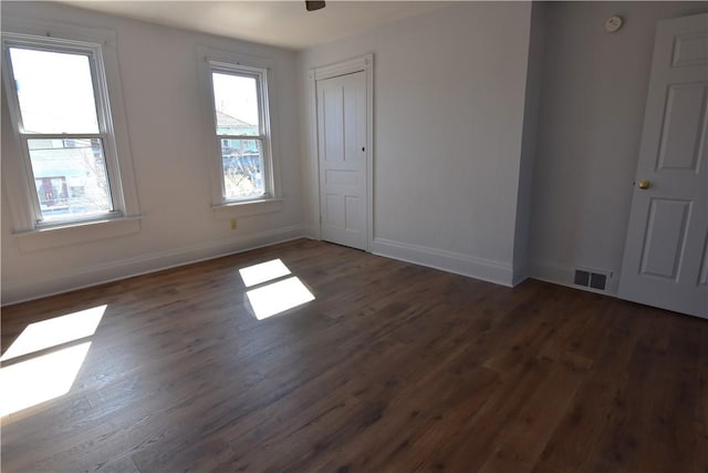 spare room with visible vents, baseboards, and wood finished floors