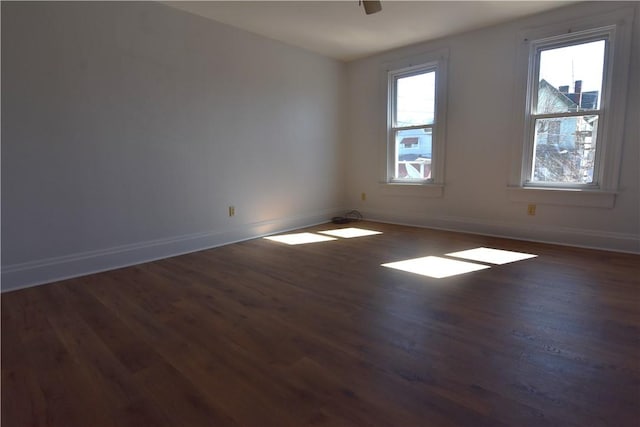 empty room with dark wood-style floors, ceiling fan, and baseboards