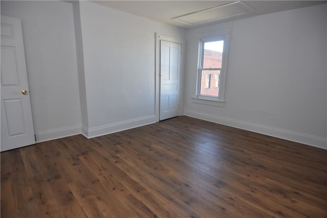 spare room with dark wood-style floors, attic access, and baseboards