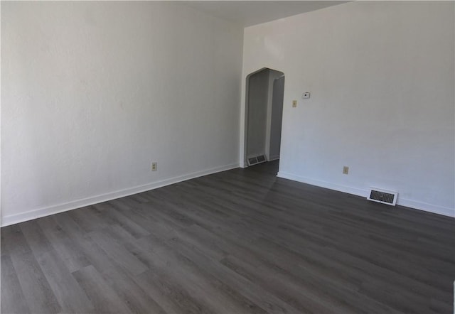 unfurnished room featuring baseboards, visible vents, and dark wood-style flooring