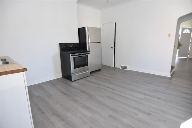 kitchen with wood finished floors, visible vents, wooden counters, arched walkways, and stainless steel appliances