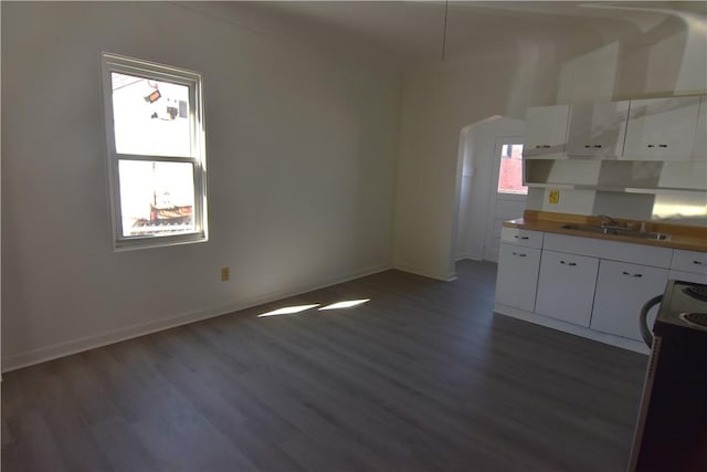 kitchen featuring a sink, range with electric cooktop, arched walkways, white cabinetry, and dark wood-style flooring