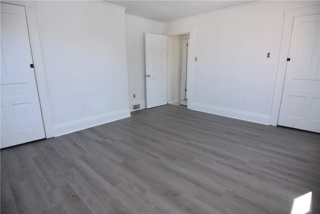 unfurnished bedroom featuring dark wood-type flooring, baseboards, and ornamental molding