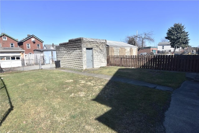 view of yard with an outdoor structure, a fenced backyard, and a shed