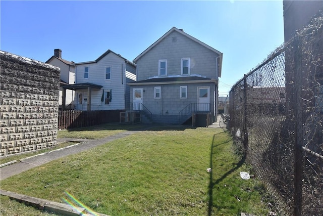 rear view of house with a lawn and fence