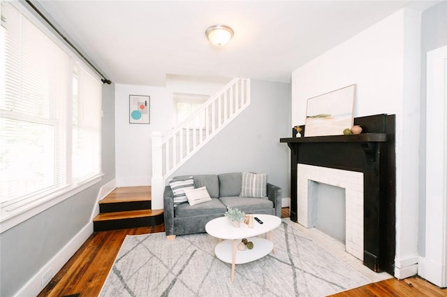 living area with baseboards, a fireplace, wood finished floors, and stairs