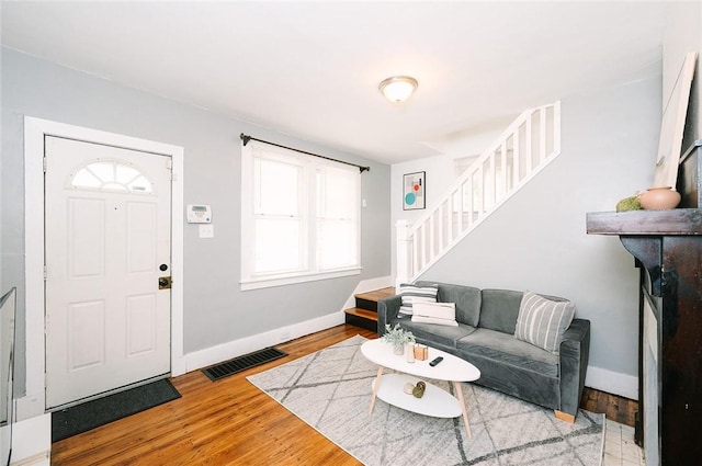 living room featuring visible vents, baseboards, wood finished floors, and stairs