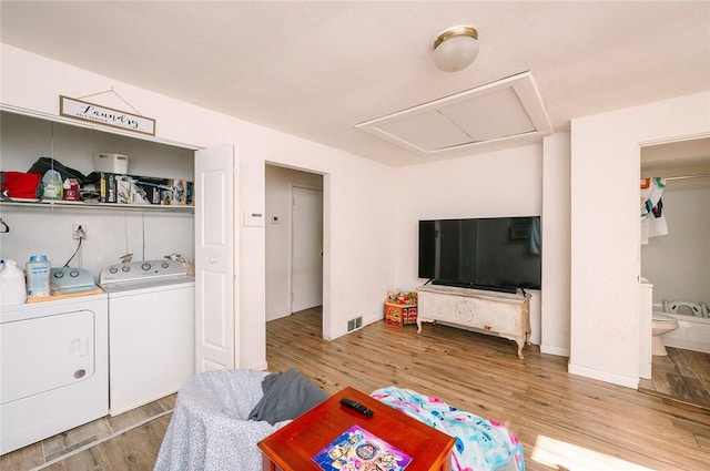 living room with attic access, light wood finished floors, and washing machine and clothes dryer