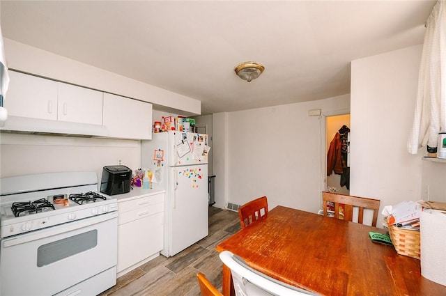 kitchen with under cabinet range hood, white cabinets, white appliances, and wood tiled floor