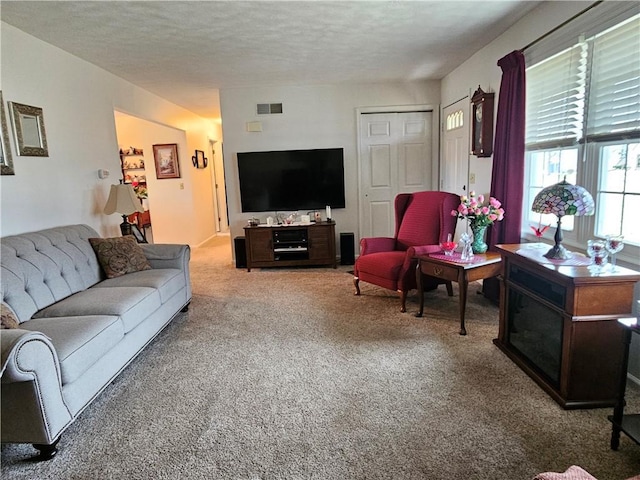 living area with carpet flooring, visible vents, and a textured ceiling