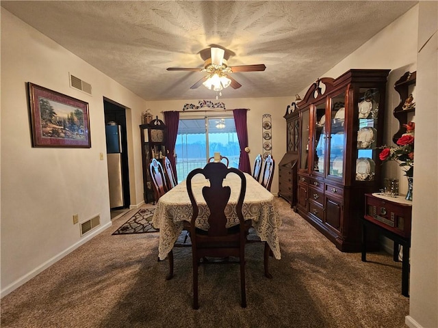 dining space with a textured ceiling, carpet, visible vents, and ceiling fan