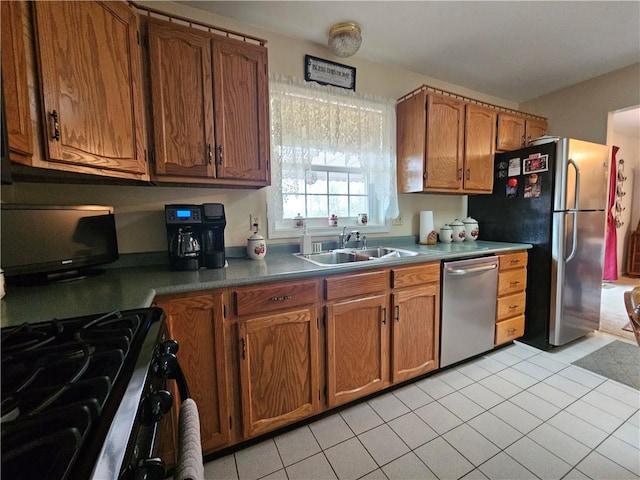 kitchen featuring a sink, light tile patterned floors, brown cabinets, and stainless steel appliances