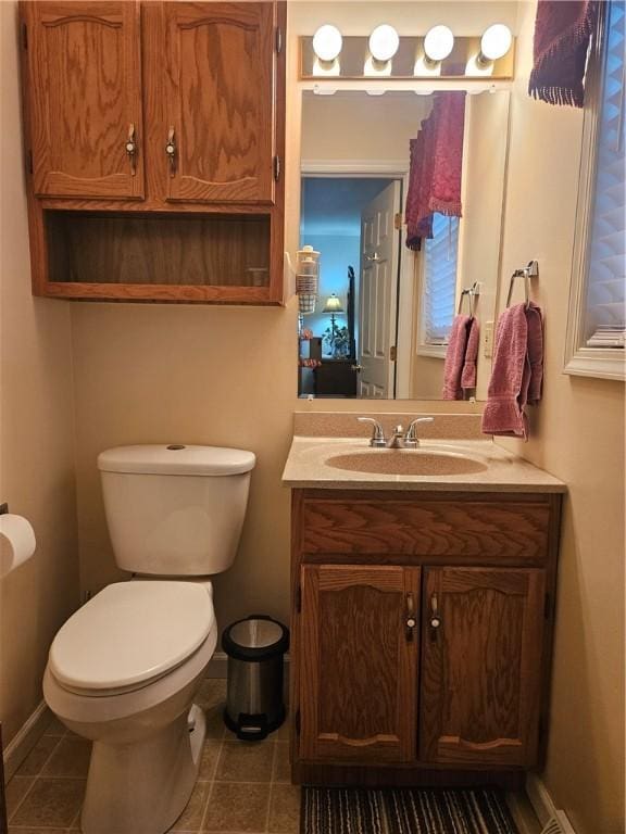 bathroom with tile patterned flooring, toilet, vanity, and baseboards