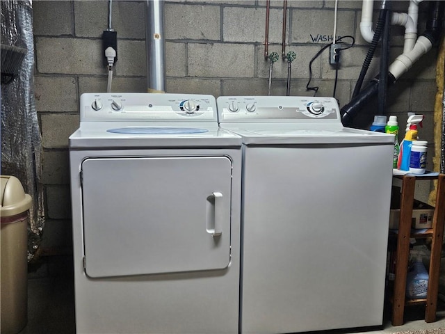 washroom with washing machine and clothes dryer, laundry area, and concrete block wall