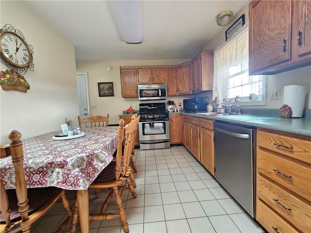 kitchen featuring light tile patterned floors, brown cabinets, appliances with stainless steel finishes, and a sink