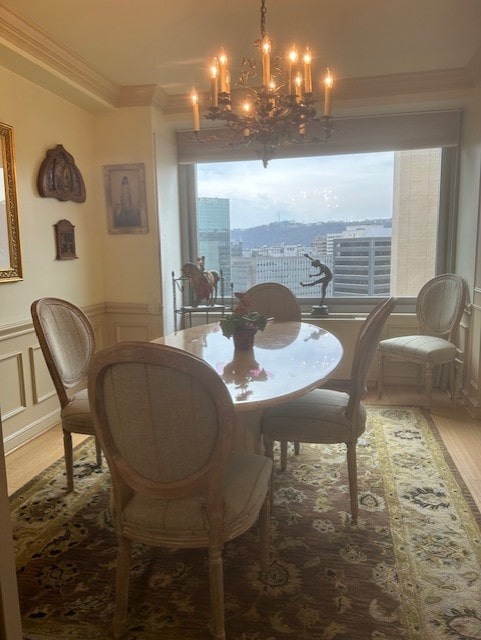 dining space with an inviting chandelier, wood finished floors, crown molding, and a decorative wall