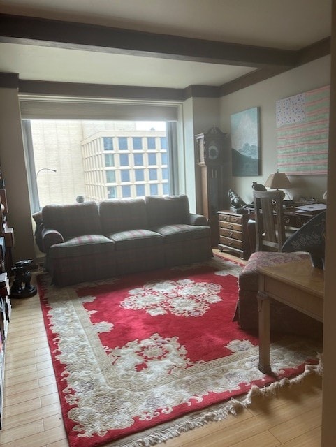 living area with beam ceiling, plenty of natural light, and wood finished floors