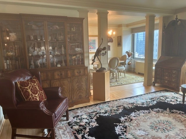 interior space featuring decorative columns, wood finished floors, and ornamental molding