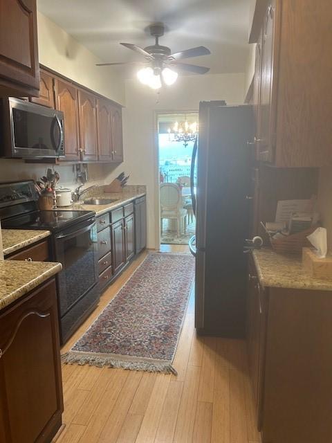 kitchen with a ceiling fan, light wood-style floors, appliances with stainless steel finishes, and a sink