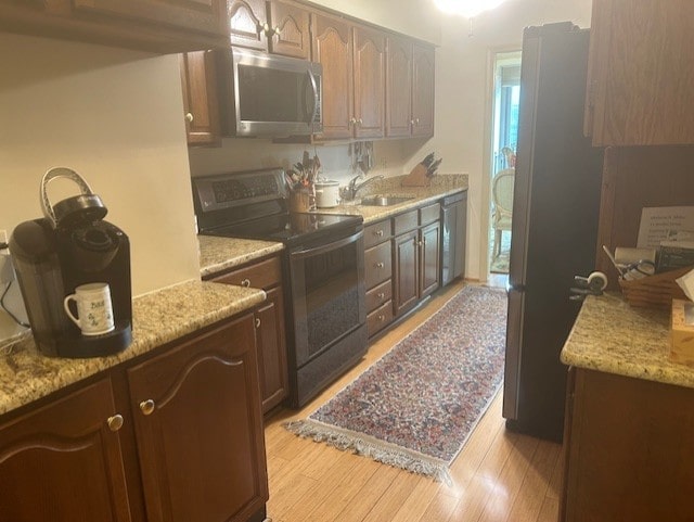 kitchen featuring a sink, stainless steel appliances, and light wood finished floors