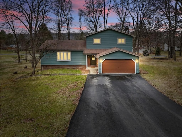 tri-level home with aphalt driveway, a lawn, and an attached garage