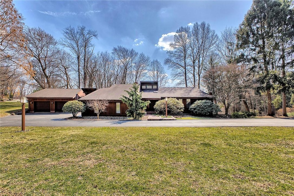 mid-century home featuring a front yard, a garage, and aphalt driveway