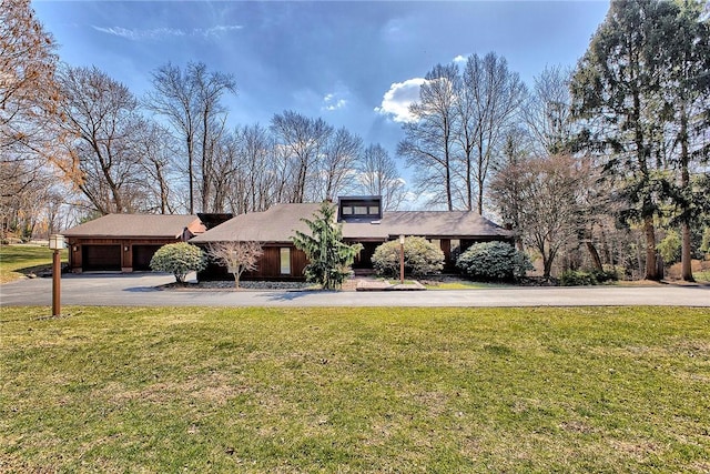 mid-century home featuring a front yard, a garage, and aphalt driveway