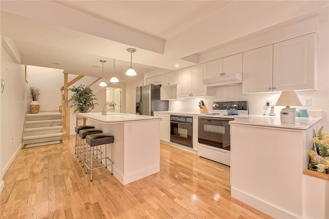 kitchen with stainless steel fridge with ice dispenser, white cabinets, under cabinet range hood, range with electric stovetop, and black oven