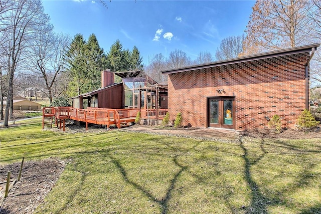 rear view of house with french doors, a yard, a wooden deck, and brick siding