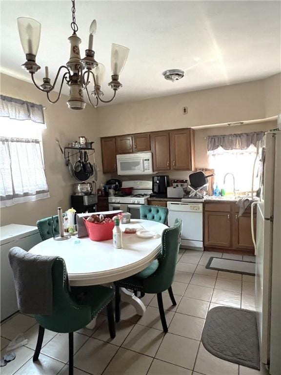 kitchen with a sink, white appliances, a chandelier, and light tile patterned flooring