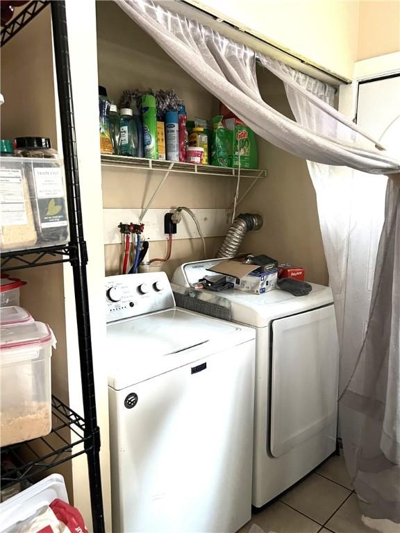 washroom featuring laundry area, light tile patterned floors, and washing machine and dryer