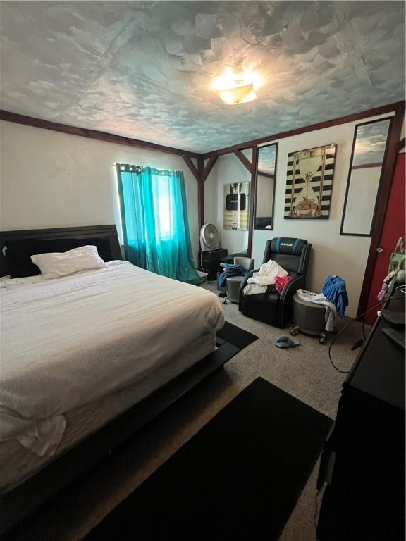 bedroom with a textured ceiling, carpet, and ornamental molding