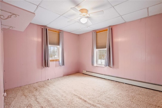 carpeted spare room with a drop ceiling, baseboard heating, and a ceiling fan