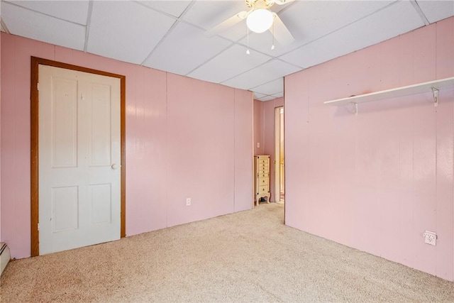 unfurnished bedroom featuring a ceiling fan, a paneled ceiling, carpet floors, and a baseboard heating unit