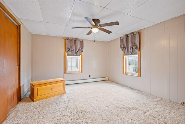 carpeted spare room with a paneled ceiling, baseboard heating, and ceiling fan