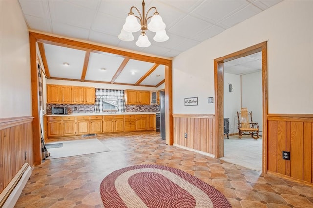 kitchen featuring a baseboard heating unit, an inviting chandelier, wood walls, and wainscoting