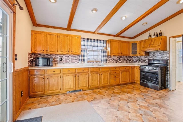 kitchen featuring visible vents, vaulted ceiling with beams, wainscoting, gas stove, and a sink