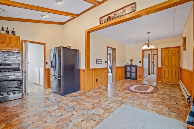 kitchen with a baseboard heating unit, beam ceiling, wainscoting, appliances with stainless steel finishes, and a notable chandelier