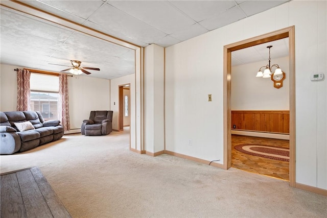 unfurnished living room with a baseboard radiator, carpet floors, baseboards, and ceiling fan with notable chandelier