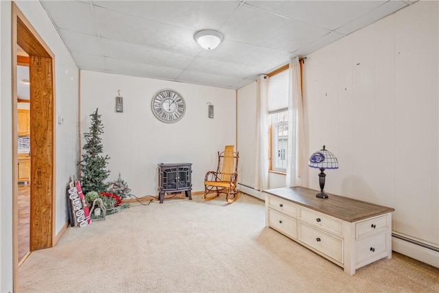 living area featuring a wood stove, light colored carpet, and baseboard heating