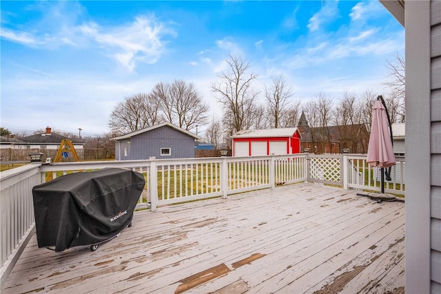 wooden deck with area for grilling, an outdoor structure, a garage, and fence