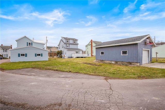 view of side of property with an outbuilding, a yard, and driveway