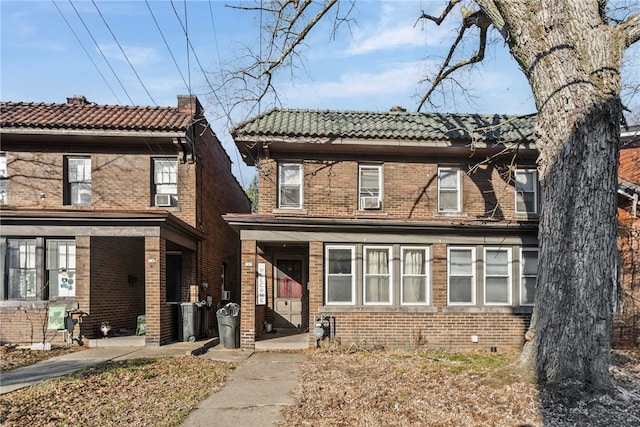 view of front facade with a tile roof, cooling unit, and brick siding