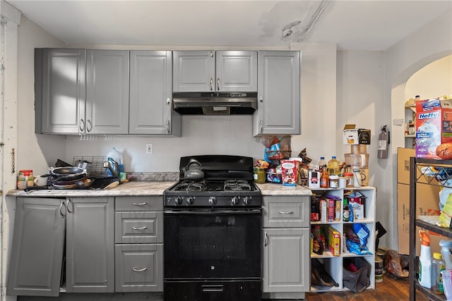 kitchen featuring light countertops, gas stove, gray cabinets, and under cabinet range hood