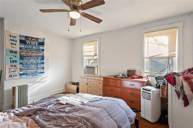 bedroom featuring ceiling fan, baseboards, radiator, and dark wood finished floors