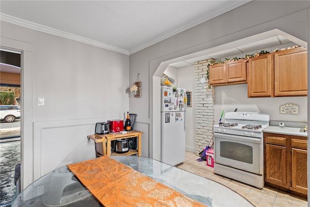 kitchen featuring white appliances, light tile patterned floors, light countertops, crown molding, and brown cabinets